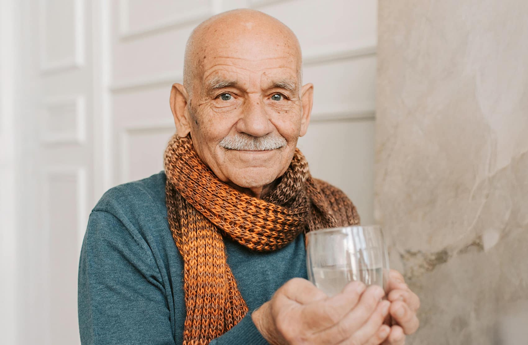 Elder Man with Bright Green Eyes Holding Water Glass