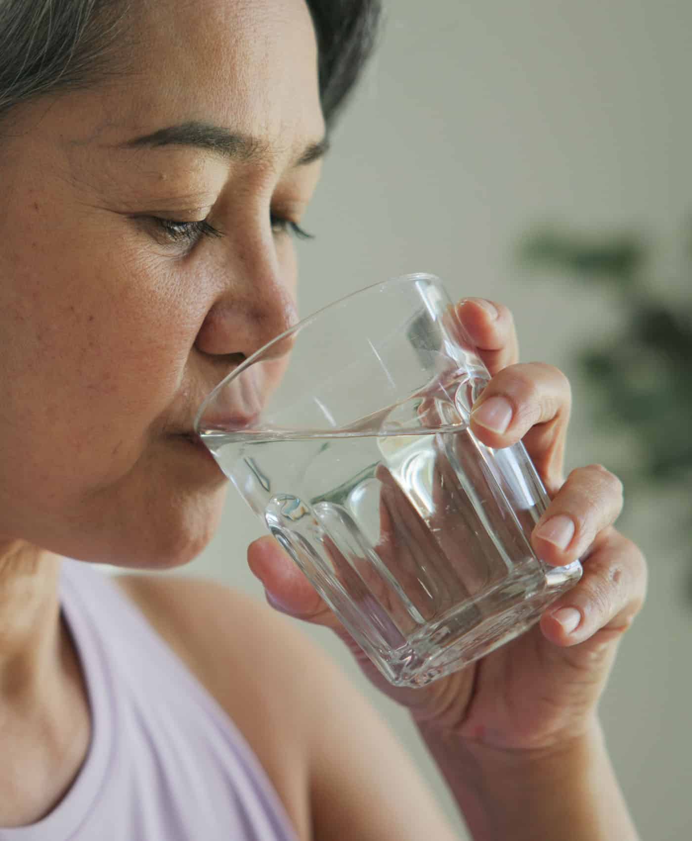 Middle Aged Asian Woman Drinking from a Water Glass