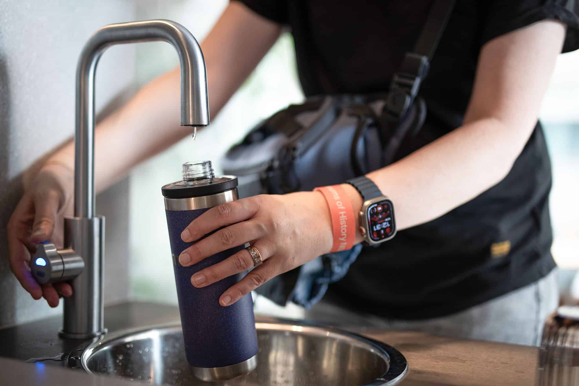 Woman Filling up a Water Bottle at home